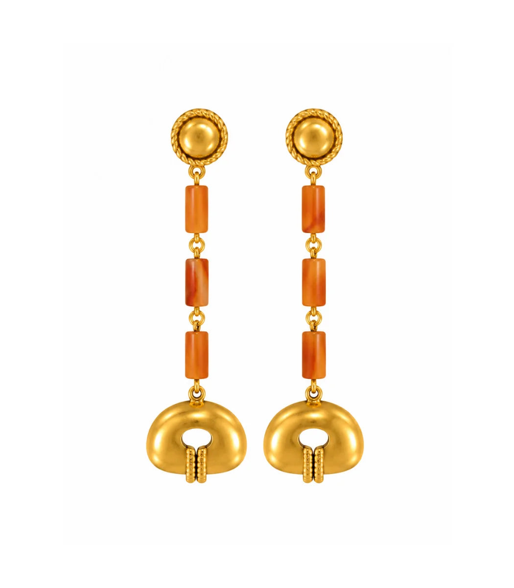 A pair of gold dangle earrings with textured circular studs, orange cylindrical spacer beads, and a large gold oval drop at the bottom, shown on a plain white background.