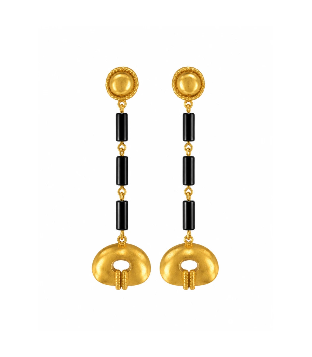 A pair of gold and black drop earrings with textured circular gold tops, black cylindrical beads, and oval gold pendants, shown on a plain white background.