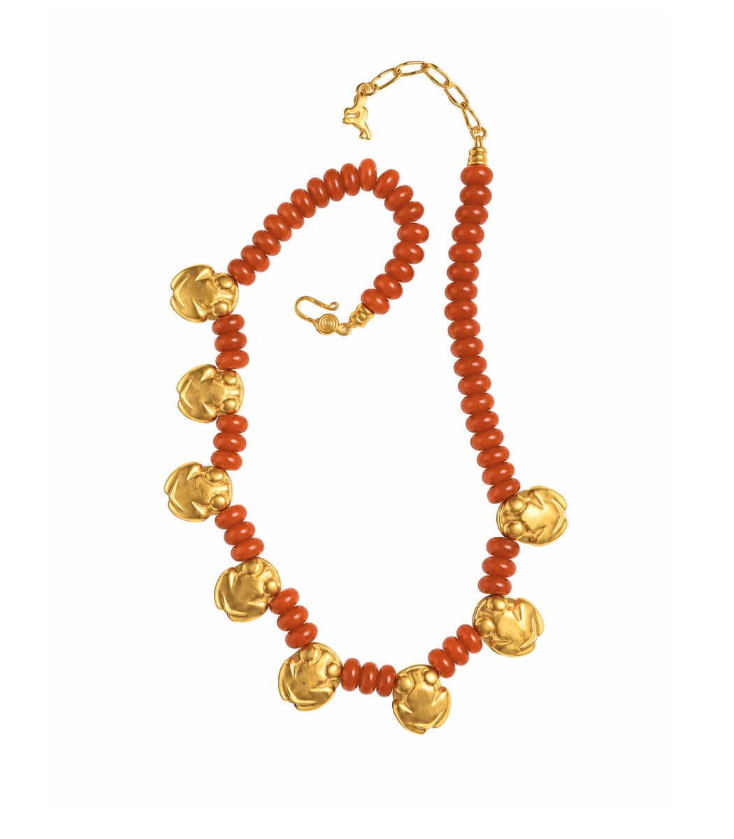 A beaded necklace featuring textured orange-red coral-like beads and polished gold-toned floral medallions, displayed on a clean white background.