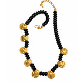 A black beaded necklace with alternating large textured gold flower-shaped beads and small black spacer beads, finished with gold hardware on a white background.