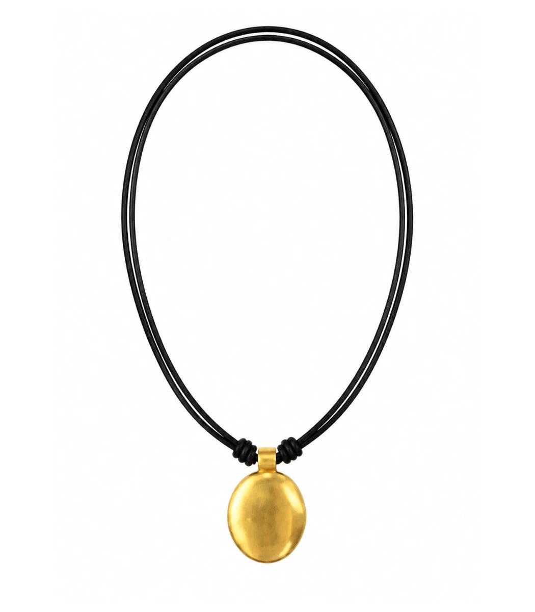A minimalist gold pendant necklace on a black multi-strand cord, shown against a plain white background.