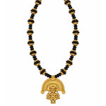 A gold and black beaded necklace featuring a detailed gold pendant with a stylized figure and semicircular design, set against a plain white background.