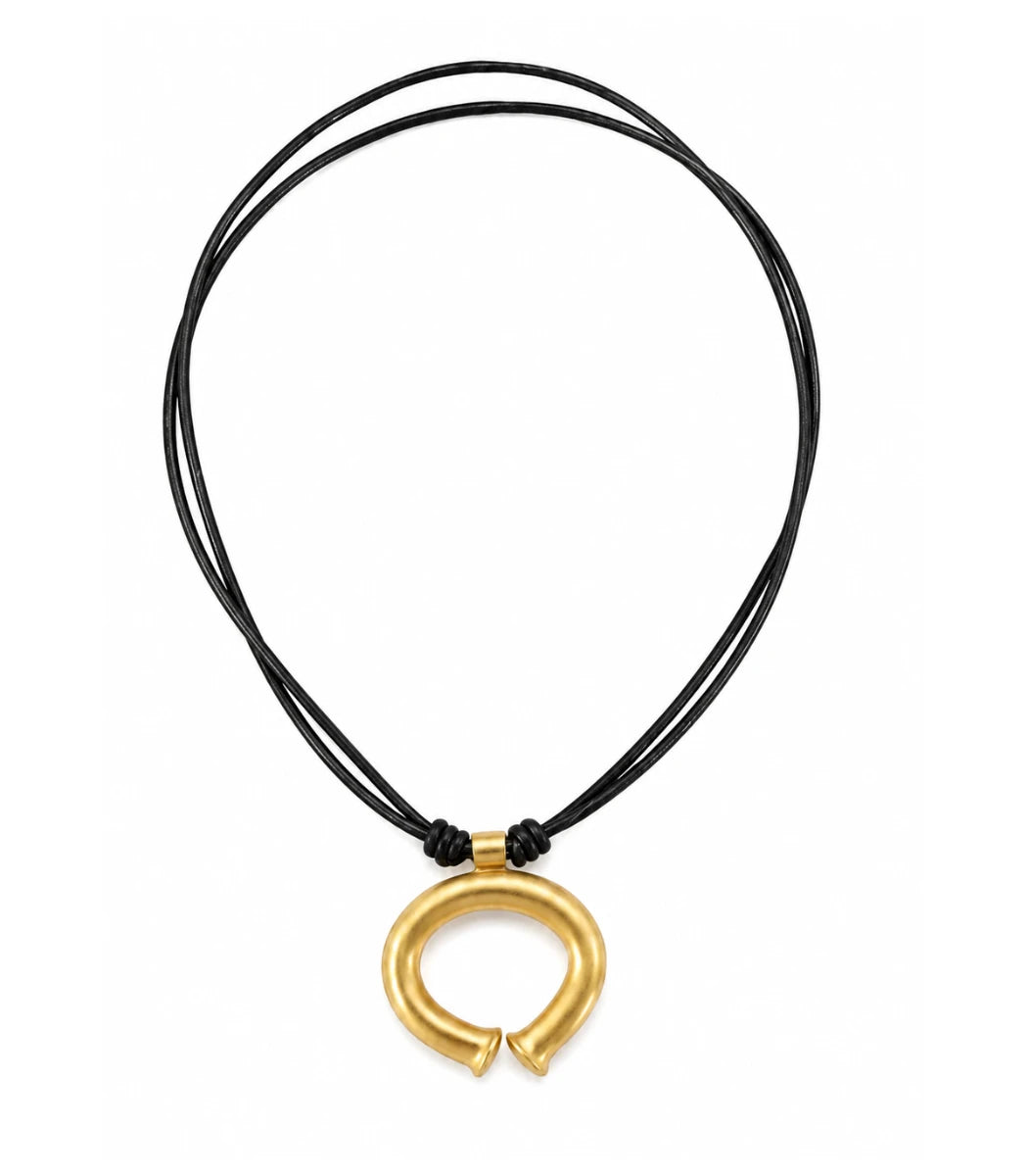 A black multi-strand cord necklace with a polished gold-toned split ring pendant, displayed on a clean white background.