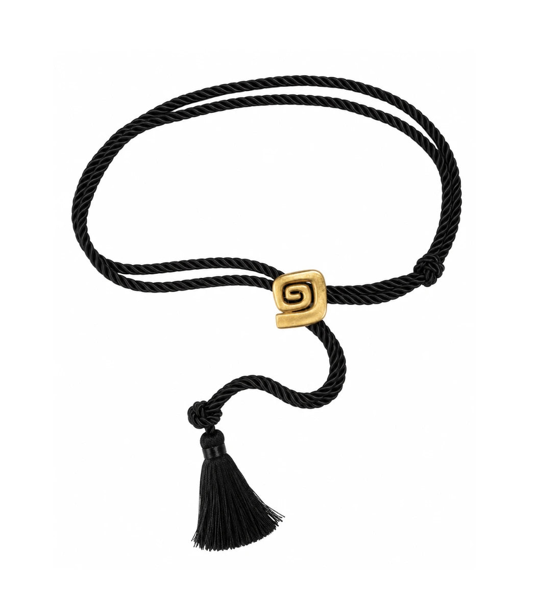 A black twisted rope bracelet with a gold square slide clasp featuring a Greek key spiral design and a matching black tassel, shown on a plain white background.