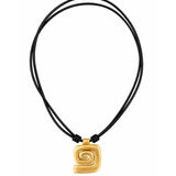 A gold spiral pendant necklace on a black multi-strand cord, shown against a plain white background.