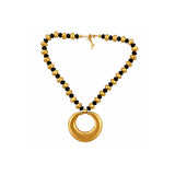 A gold-tone beaded necklace with alternating polished round beads and smaller faceted beads, featuring a large open circular pendant at the center, shown on a plain white background.